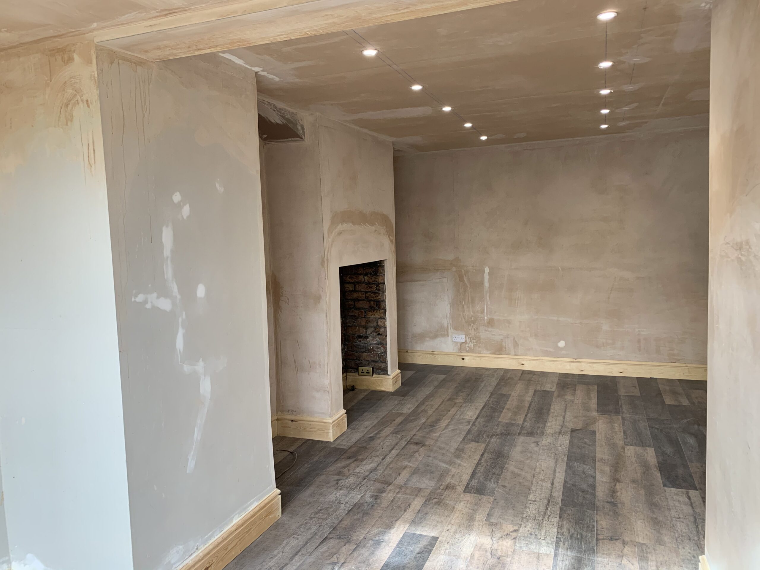 freshly plastered living room with new skirting boards and hardwood flooring